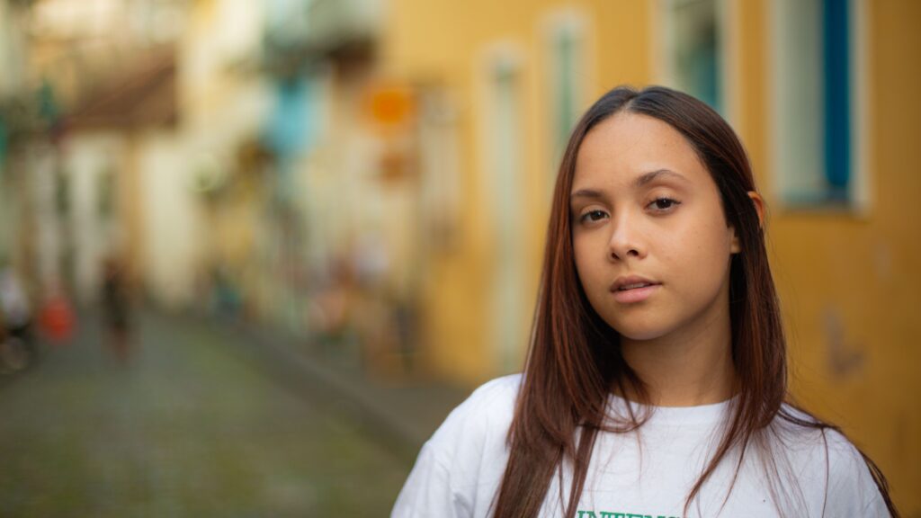 A close-up portrait of a woman in Salvador, Brazil's vibrant streets with a blurred background.